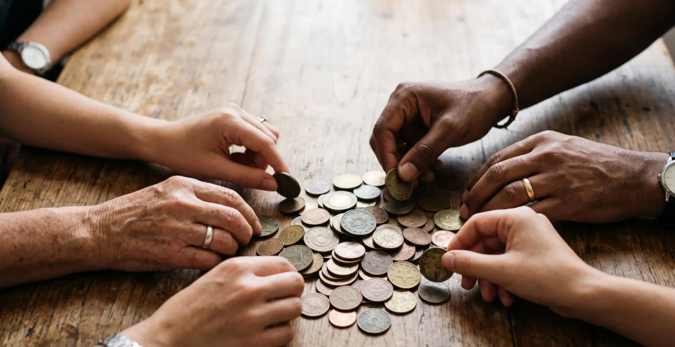 Des mains diverses deposant chacune une piece sur une pile grandissante symbolisant la collecte de financement participatif