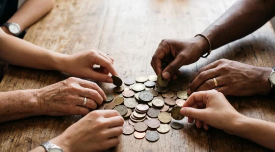 Des mains diverses deposant chacune une piece sur une pile grandissante symbolisant la collecte de financement participatif